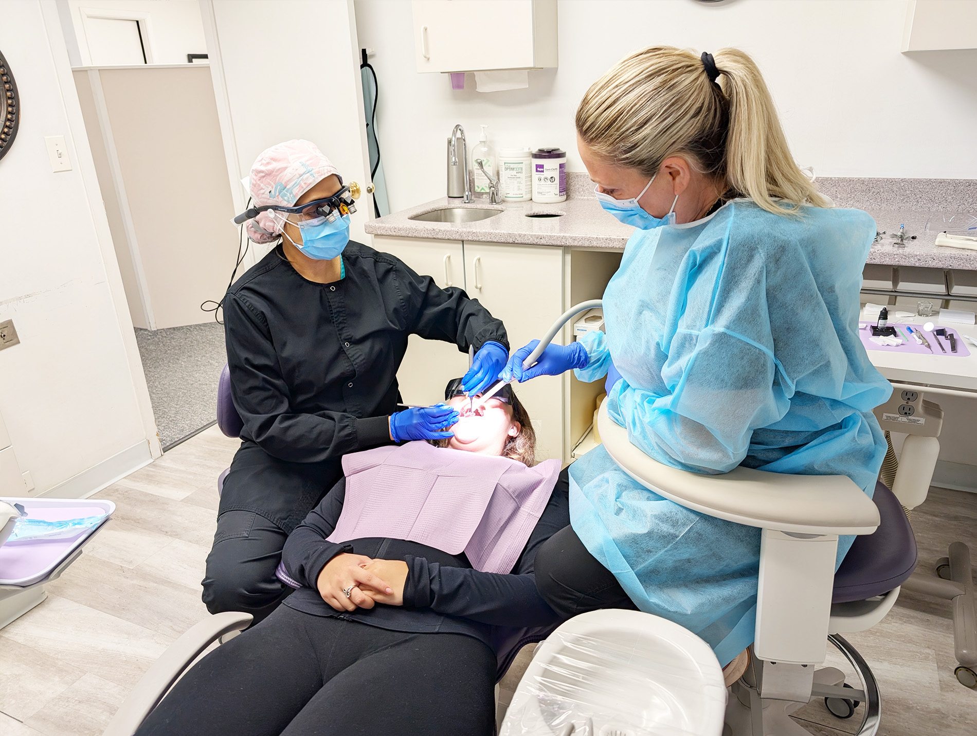 A dental hygienist is performing oral care on a patient in a dental office setting.