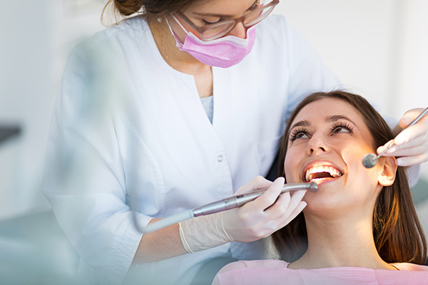 The image shows a dental professional assisting a patient during a dental appointment.