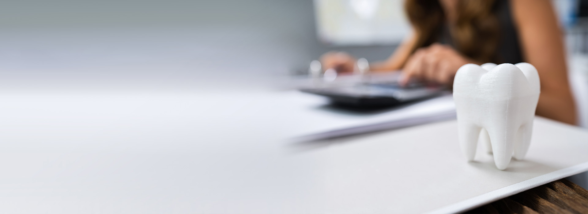 A person working at a desk with a laptop, pen, and toothbrush holder in the foreground.