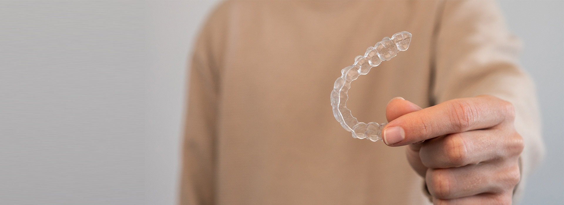 The image shows a person holding an object with bubbles, which appears to be soap or some kind of bubble-producing substance, against a plain background.