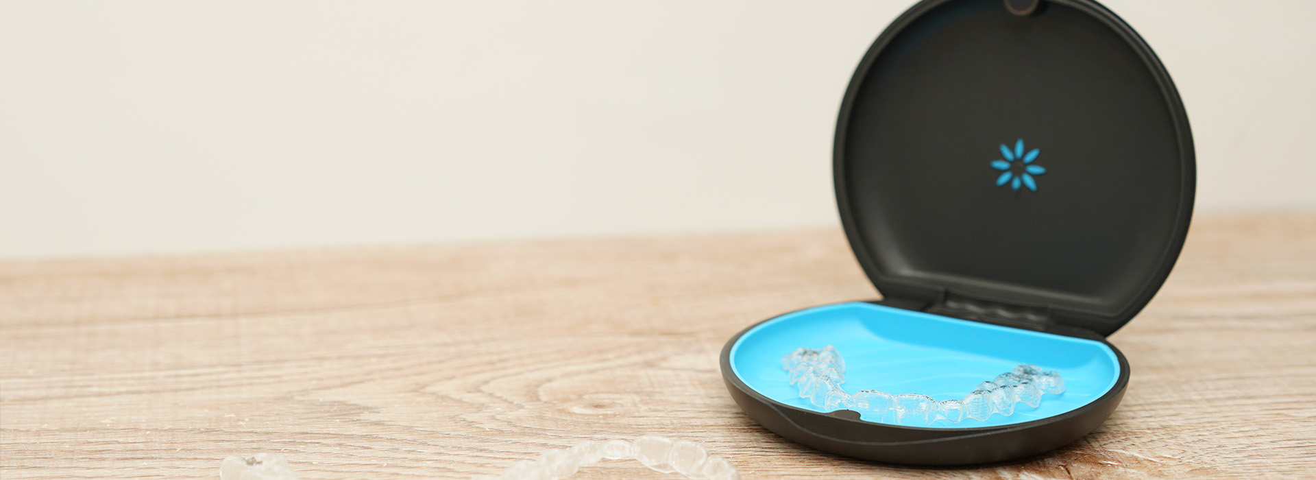 The image shows a small, blue smart home device with a camera lens on top, placed against a wooden surface on the right side.