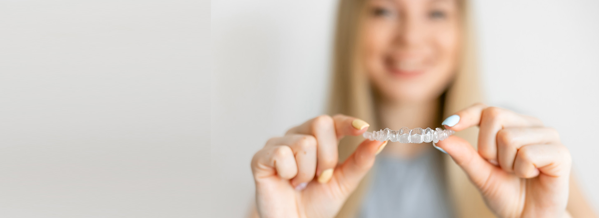 A woman holding up a piece of jewelry against her chest with a smile on her face.