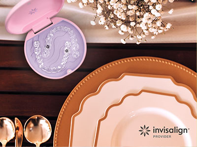 The image shows a collection of tableware items, including plates, a serving dish, and a spoon rest, displayed on a wooden surface with a pink toothbrush holder in the background, suggesting an arrangement for a meal or event.