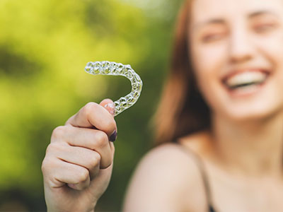 A smiling woman holding a transparent toothbrush with bristles.