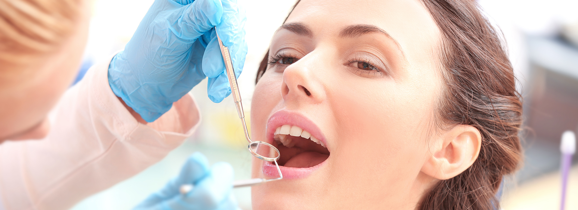 A woman receiving dental care with a dentist using tools on her mouth.