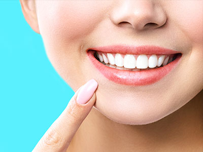 The image features a close-up of a person with a bright smile, showcasing their teeth and facial expression, against a light blue background.